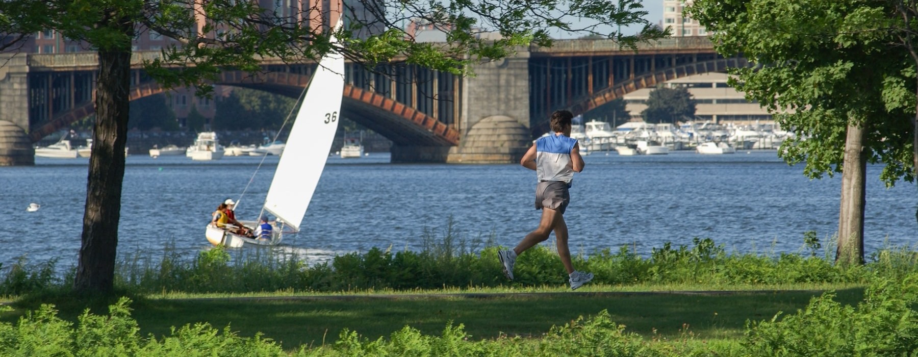 a person running on a path next to a sailboat