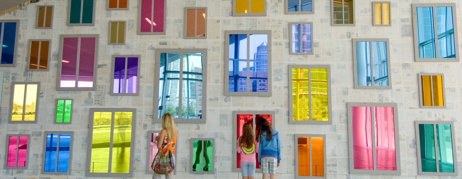 a group of people standing in front of a building with many windows